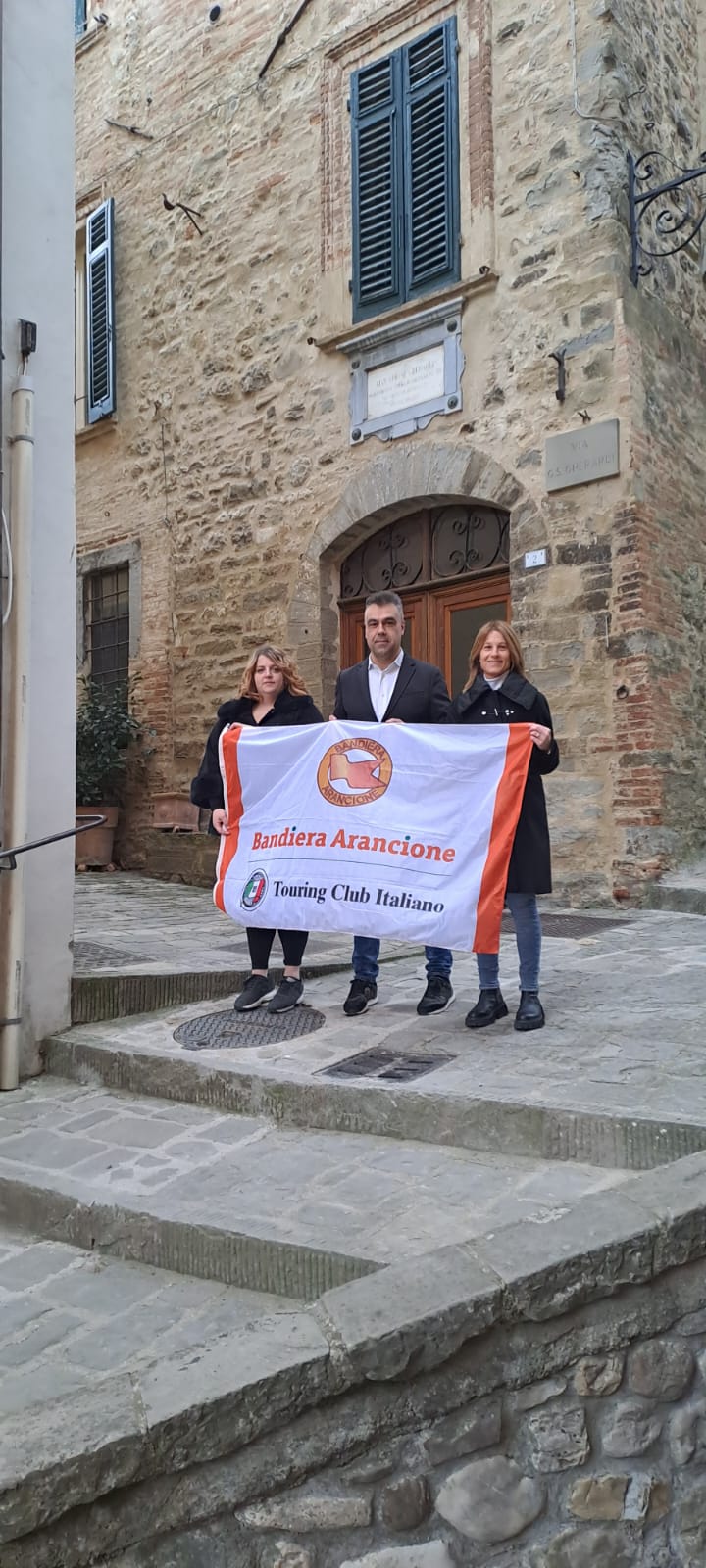 immagine della Bandiera arancione del Touring Club tenuta dal sindaco Rinaldi insieme alla sua vice Rosini e all'assessora Volpi